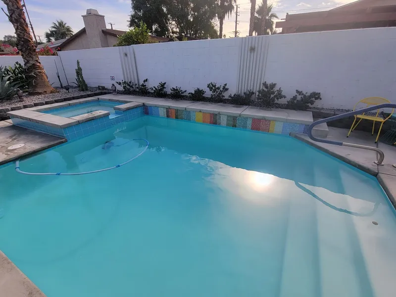 A pool and spa with a multicoloured tile waterline band