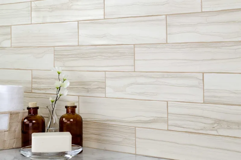 Cream and taupe wood-vein marble-look plank tile behind a marble vanity top