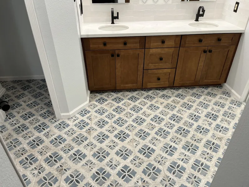 Blue and white patterned floor tile across a bathroom with a walnut double vanity