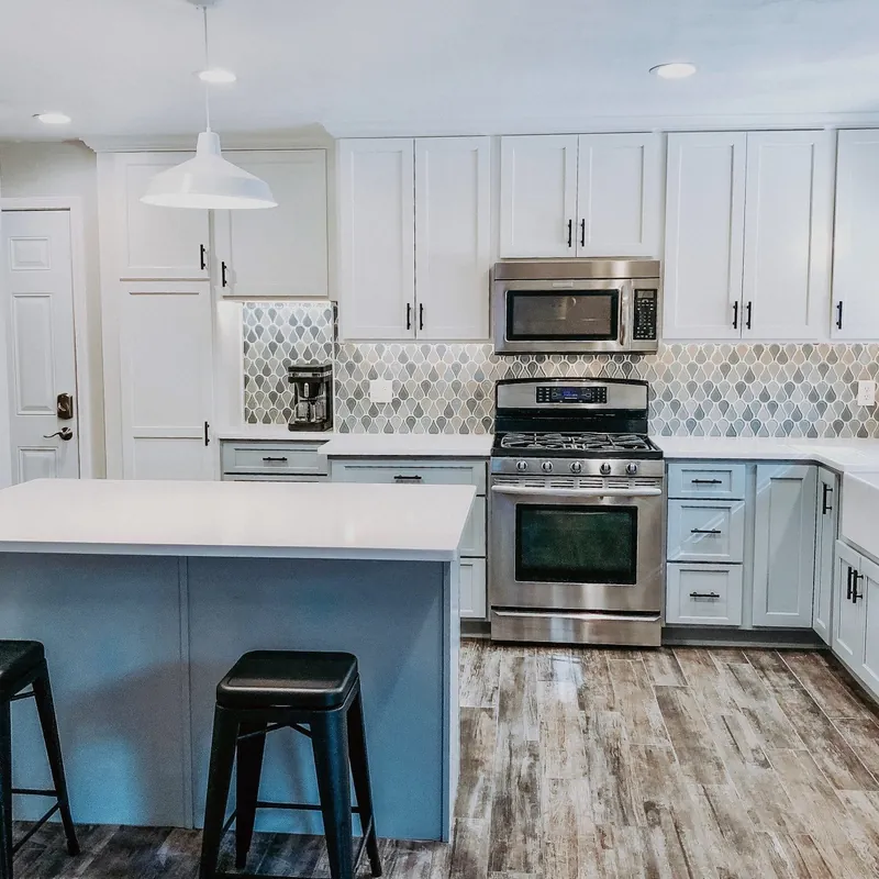 A kitchen with white shaker cabinets and a teardrop mosaic backsplash