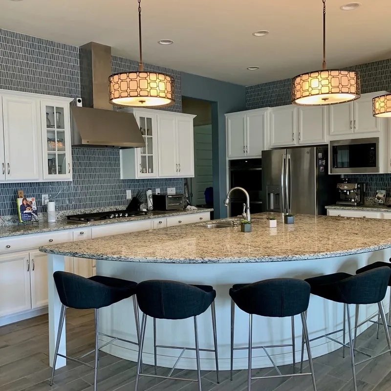 A kitchen with white cabinetry and a blue geometric mosaic backsplash