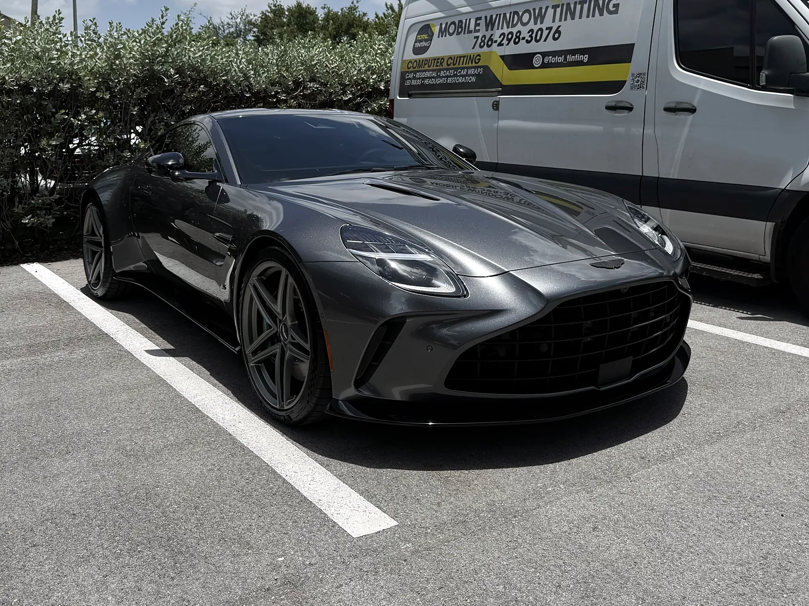 Aston Martin with fresh tint beside the lettered Total Tinting mobile van