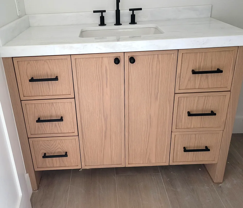 Oak shaker vanity with matte black knobs and pulls.