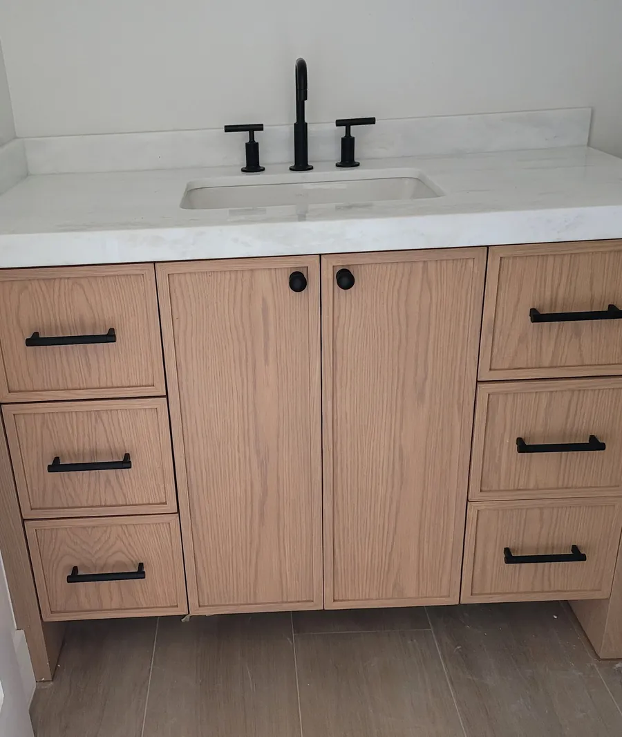 The oak shaker vanity these doors came from, with black knobs and pulls under a white stone top.